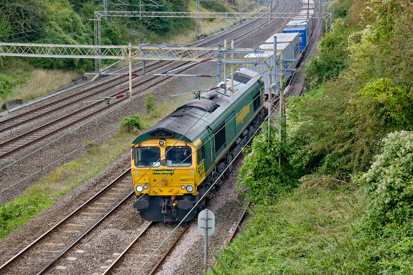 66572, 12.30 Crewe Basford Hall-Felixstowe North (4L90), Victoria bridge 
 Just a few minutes after the previous photograph of 66414 was taken 66572 heads south with the 12.30 Crewe Basford Hall to Felixstowe Freightliner train. Creating a lot of exhaust the locomotive is picking up speed after the long and steady climb from Northampton as it passes Victoria bridge near Roade. As well as being in dubious mechanical condition it appears to be in need of a visit to the paint shop with a huge scab of rust evident between the windscreens! 
 Keywords: 66572 12.30 Crewe Basford Hall-Felixstowe North 4L90 Victoria bridge Freightliner