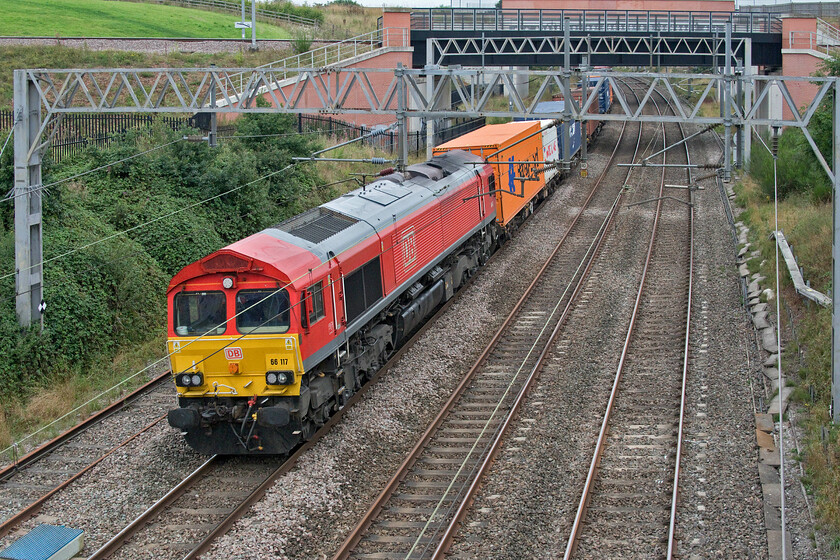 66117, 09.15 Trafford Park-Southampton Western Docks (4O21, 3E), Norton Bridge SJ867303 
 66117 brightens an otherwise grey and dull morning leading the 09.15 Trafford Park to Southampton Freightliner service. The two bridges in the background were constructed between 2014 and 2016 as part of the grade separation programme to rebuild Norton Bridge Junction. The first bridge directly behind the train is designated 5 and it carries the double tracks of the route to Stone and Stoke whilst the second bridge, 5a carries the re-routed B5026 road that used to cross the bridge that I am standing on. 
 Keywords: 66117 09.15 Trafford Park-Southampton Western Docks 4O21 Norton Bridge SJ867303 DB