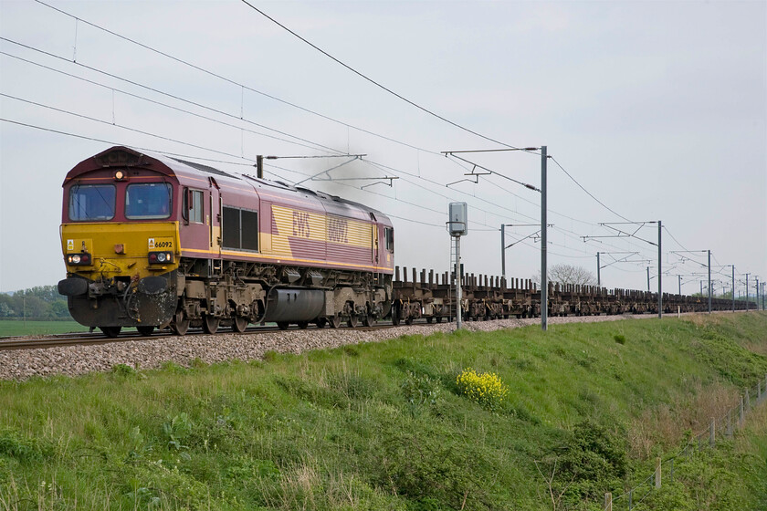 66092, 12.05 Dollands Moor-Scunthorpe Redbourne (4E32), Frinkley Lane crossing SK906436 
 66092 makes, what would seem to be, some excess exhaust hauling a relatively light and unloaded train as it passes Frinkley Lane crossing just north of Grantham. The EWS liveried Class 66 is hauling the 4E32 12.05 Dollands Moor to Scunthorpe steel empties. 66092 arrived on our shores in April 1999 and in its fifteen-year life has gone about its business in a pretty anonymous fashion with the highlight probably being it hauling a short section of The Cornubian railtour in 2002, see..... http://www.sixbellsjunction.co.uk/00s/021221pt.htm 
 Keywords: 66092 12.05 Dollands Moor-Scunthorpe Redbourne 4E32 Frinkley Lane crossing SK906436