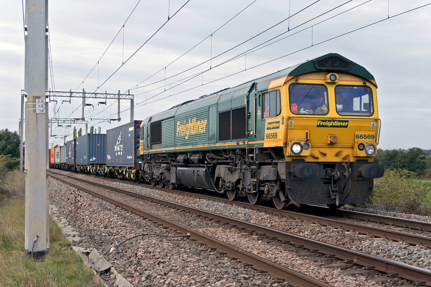 66569, 12.16 Lawley Street-London Gateway (4L62, 1E), Wilson's Crossing 
 Whilst Wilson's Crossing remains a reasonable proposition for photographing down trains ups are more difficult to capture due to the awkward placing of an electrification post! 66569 leads the 12.16 Lawley Street to London Gateway 4L62 Freightliner on the northern approach to Northampton. 
 Keywords: 66569 12.16 Lawley Street-London Gateway 4L62 Wilson's Crossing Freightliner