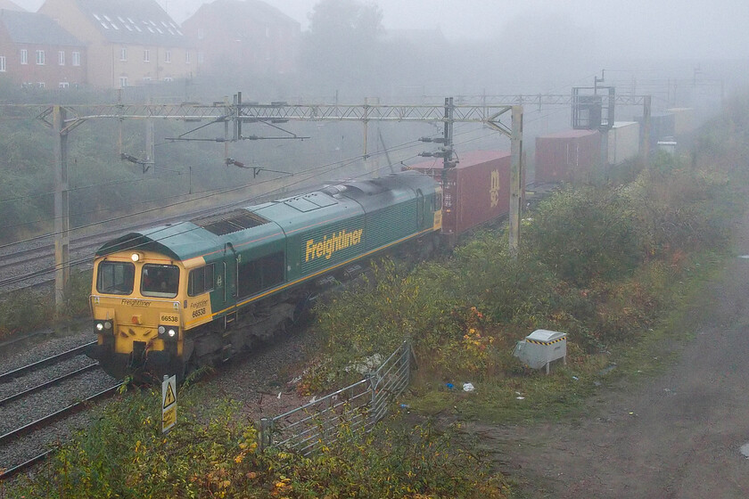 66538, 03.21 Garston-Felixstowe North (4L41, 4E), site of Roade station 
 The 4L41 03.21 Garston to Felixstowe Freightliner passes Roade emerging from the depths of the fmous cutting. On this foggy autumnal Friday morning regular performer 66538 is leading the train. Following the passage of this train Andy and I made our way home and I headed off to work. 
 Keywords: 66538 03.21 Garston-Felixstowe North 4L41 site of Roade station Freightliner