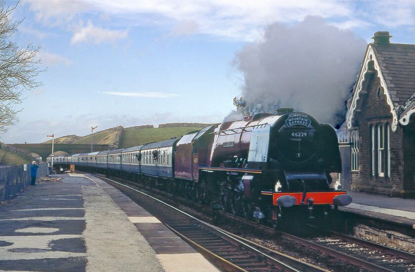 4. 46229, outward leg of The Cumbrian Mountain Express, Carlisle-Hellifield, Kirkby Stephen station 
 Having raced from Keld just north of Appleby in the Austin 1100 passing The Cumbrian Mountain Express which was held at Appleby station for a photo stop we just managed to get it passing Kirkby Stephen. 46229 'Duchess of Hamilton' is seen passing through the closed station working hard on the northern assault of the Settle and Carlisle line. Since leaving Appleby some ten miles south of this location the train had been climbing at a steady 1:100 with the Coronation Class working well keeping the train moving at a very reasonable rate. The former Midland Railway station at Kirkby Stephen (formally Kirkby Stephen West until 1968) had been closed for eleven years when this photograph was taken. With the official saving of the S & C still some years away it was five years until it was reopened along with most of the other ones on the line. 
 Keywords: 46229 The Cumbrian Mountain Express Carlisle-Hellifield LMS Princess Coronation Class Duchess of Hamilton Kirkby Stephen