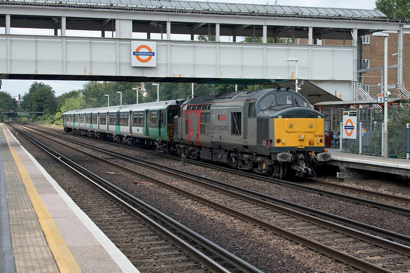 37884 & 455816, 11.00 Wolverton-Stewart s Lane, Kensington Olympia station 
 Whilst waiting for our train back to Milton Keynes, the green signal cleared on the southbound line through Kensington Olympia and the familiar sight of 37884 'Cepheus' appeared in the distance. The Rail Operations Group class 37 was towing Southern's 455816 back from Wolverton works to Stewert's Lane depot with it having had scheduled repairs undertaken. This is a regular Saturday morning working with another unit heading north in the afternoon to have work undertaken the over the following week. The class 37s are ideal for such moves given their flexibility and light axle loadings, not bad when one remembers that they are over fifty years old! 
 Keywords: 37884 455816 11.00 Wolverton-Stewart's Lane Kensington Olympia station