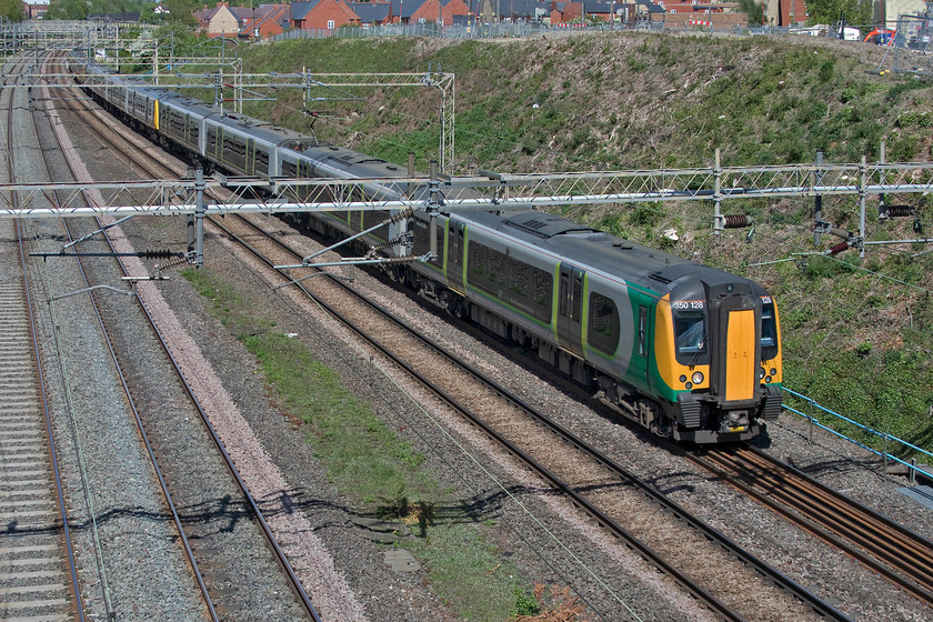 350128, LN 11.45 Northampton-London Euston (2N34, RT), Ashton Road bridge 
 350128 and two classmates are about to pass under Ashton Road bridge just south of Roade with the 11.45 Northampton to Euston 2N34 service. This is a tricky spot to take pictures from as without a ladder the parapet is so high that I can't see over to get a shot. Therefore, I have to use the camera at arms length with the flip-out screen angled down towards me and hope for the best. In this particular instance I got things about right. It's just a shame that the sun was not just a little bit more round to illuminate the body side. 
 Keywords: 350128 11.45 Northampton-London Euston 2N34 Ashton Road bridge London Northwestern desiro