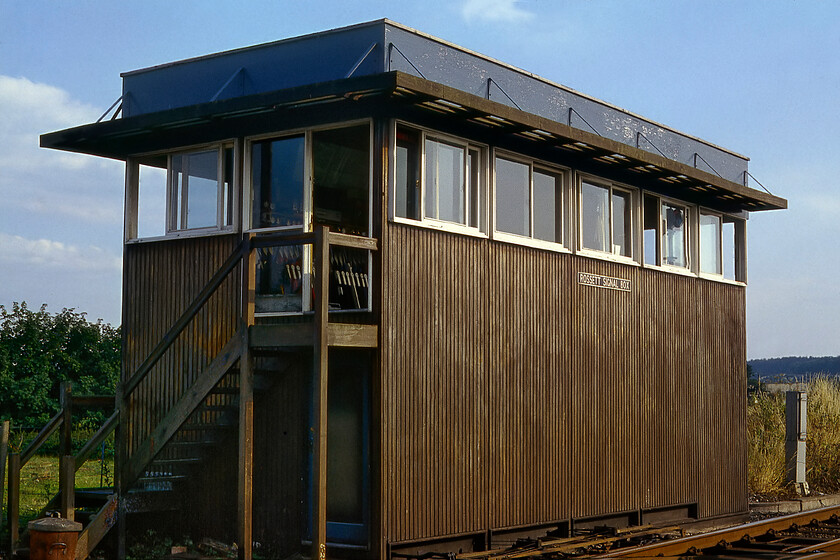 Rossett signal box (BR, 1960) 
 Rather disparagingly referred to as 'plywood wonders' the British Railways (Western Region) boxes built in the 1950/60s era were a cost-effective way of replacing a life-expired or damaged box. Further examples could be found at other locations, for example.... https://www.ontheupfast.com/p/21936chg/25386595404/x50031-up-working-hungerford-station. They were pretty much universal in their design that could be positioned either way round and with doors pre-installed at either meaning that the steps could be positioned easily as appropriate to the site. Rossett signal box replaced an earlier GW box that was located on the other side of the track and the level crossing on which I am standing to take this photograph. Rossett station closed in October 1964 and by the time of our visit here in 1981, all that remained were the platforms that still saw very occasional use by specials conveying pupils to and from the nearby Moreton Hall Girls' school. By 1986 the line through the station was singled but this was again doubled during 2016 between here and Saltney Junction (Chester). 
 Keywords: Rossett signal box