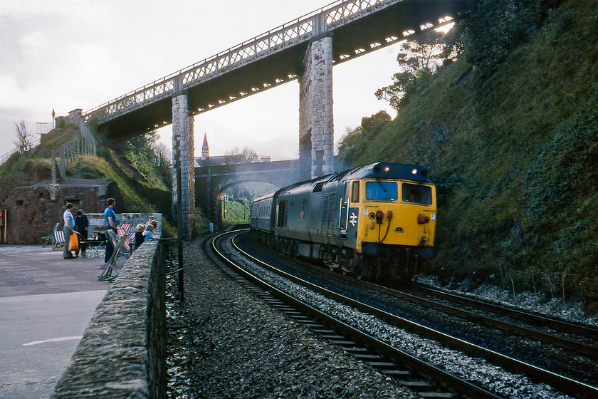 50035, 16.15 St. Austell-Kensington Olympia Motorail, Teignmouth sea wall 
 Unfortunately, by the time Graham and I reached Teignmouth, it was late afternoon and the sun had disappeared behind the landward side of the famous sea wall thus making decent photographs tricky. 50035 'Ark Royal' leads the 16.15 St. Austell to Kensington Olympia Motorail service away from Teignmouth no doubt taking holidaymakers and their cars home after their holiday in the South-West. Once again I have failed to capture one of the Motorails without the actual car flats being in the photograph! I like this particular photograph due to the personal interest element to the left illustrating the enduring attraction that trains have with adults and children alike. Also, on view, are a number of deck chairs have been placed right next to the line so that people, as well as looking out to sea and enjoying their sandwiches and flask of tea can be close to the trains! 
 Keywords: 50035 16.15 St. Austell-Kensington Olympia Motorail Teignmouth Sea Wall Ark Royal