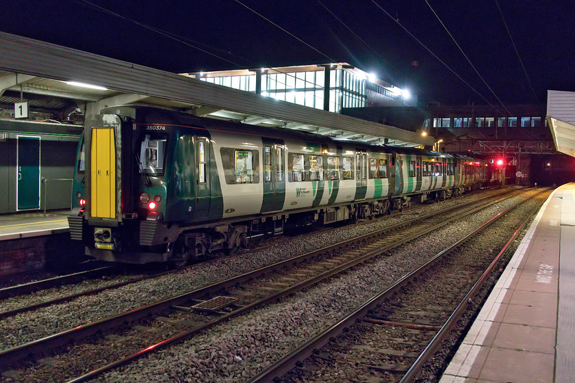 350374, LN 16.33 Birmingham New Street-London Euston (1W22), Northampton station 
 With the main building of Northampton's new station brightly lit and towering above it 350374 waits to leave for Euston with the 16.33 from Birmingham New Street. With most of these 350 unit in their awful revised livery photographing them at night (and many other conditions for that matter) has become much more tricky. The huge slab of drab green covering their ends does not lift them out from the background. Let's hope that a graphic designer sees sense soon and that London Northwestern or their parent company, West Midlands Trains, come up with a better colour scheme! 
 Keywords: 350374 16.33 Birmingham New Street-London Euston 1W22 Northampton station