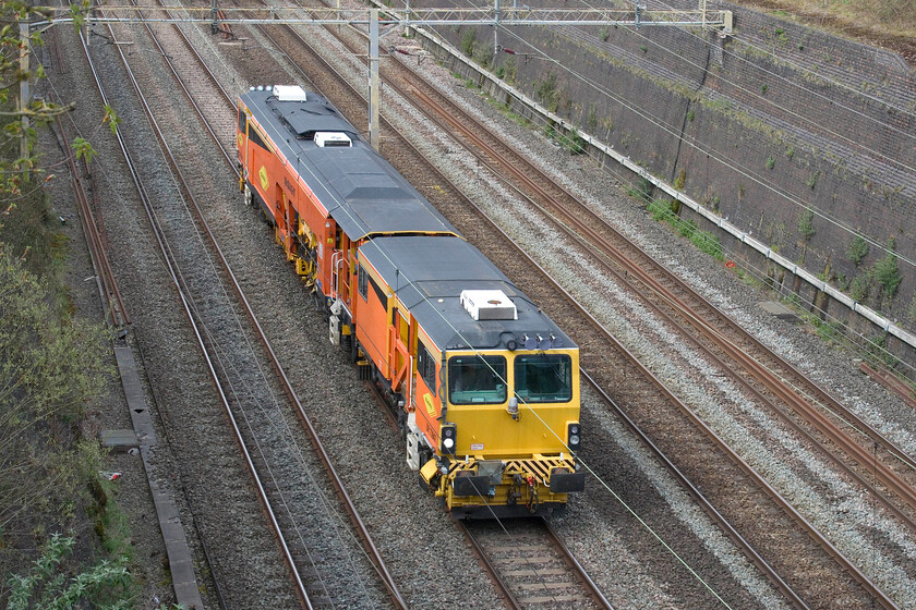 DR73947, 14.13 Nuneaton Civil Engineers-Milton Keynes Central (6J62, 3L), Roade cutting 
 Normally the movement of a track machine would not attract my attention but as the slow lines were shut DR73947 was forced to make its journey on the up fast via the Weedon route. With a timed maximum speed of sixty miles per hour, this would be a challenge for signallers as there would inevitably be problems behind the train with the following services checked. Indeed, the 14.13 Nuneaton to Milton Keynes did cause some problems with a parade of Pendolinos caught up in its wake running on caution for some distance. The Colas-operated Plasser & Theurer 08-4x4/4S-RT Switch & Crossing Tamper is seen passing through Roade cutting. 
 Keywords: DR73947 14.13 Nuneaton Civil Engineers-Milton Keynes Central 6J62 Roade cutting