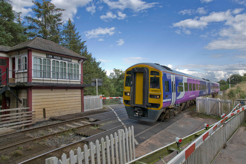 158861, NT 14.49 Leeds-Carlisle (2H92), Low House crossing 
 After what had been, ostensively, a grey summer's day the sky is now clearing and some pleasant afternoon sunshine is now the offing. 156861 rushes past Low House signal box and its associated level crossing working the 2H92 14.49 Leeds to Carlisle Northern service. To take this photograph I am standing on a conveniently placed mound of land giving just a little bit of height. 
 Keywords: 158861 14.49 Leeds-Carlisle 2H92 Low House crossing Northern