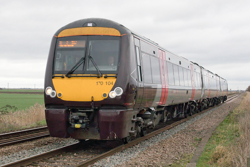 170104, XC 10.25 Stansted Airport-Birmingham New Street (1N51, 1L), Three Horse Shoes no.3 level crossing 
 More usual fare for this straight and flat bit of Fenland railway are CrossCountry services such as this one. 170104 passes Three Horse Shoes no.3 level crossing forming the 1N51 10.25 Stansted Airport to Birmingham New Street. Just in the background behind the train can be seen Three Horse Shoes no.2 level crossing and just beyond that, out of sight is no.1! 
 Keywords: 170104 10.25 Stansted Airport-Birmingham New Street 1N51 Three Horse Shoes no.3 level crossing