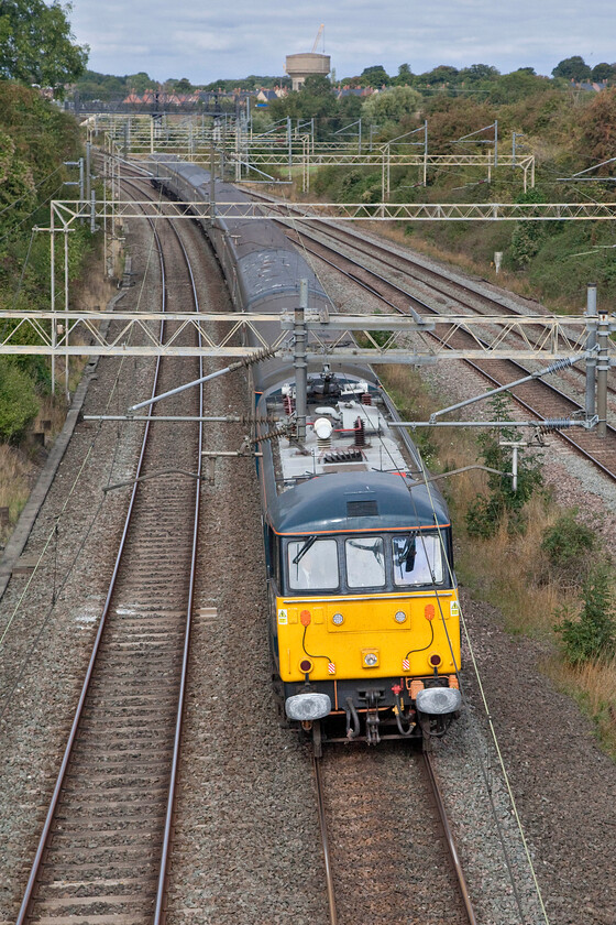 86401, 08.15 Lancaster-London Euston (1Z86, 1E), Victoria bridge 
 86401 'Mons Megg' passes Victoria bridge in South Northamptonshire leading the West Coast Railway operated 08.15 Lancaster to Euston service on behalf of Avanti West Coast. The return of locomotive hauled services has been an extraordinary turn of events with passengers once again able to enjoy the luxury of 'proper' trains with comfortable seats and unrestricted views as they travel! Notice in the background of this photograph the tall crane towering above the water tower. This has been installed above Roade cutting in connection with the installation of a new bridge spanning the cutting that will carry Roade's bypass. 
 Keywords: 86401 08.15 Lancaster-London Euston 1Z86 Victoria bridge Mons Megg AL6