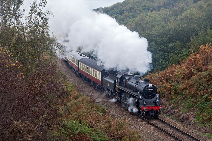 76084, 10.00 Sheringham-Holt, Kelling bank 
 What a difference a day makes! After a couple of days of lovely autumnal whether the cloud has rolled in and it's raining! Steaming well as it ascends Kelling bank Standard 4MT 76084 makes easy work leading the 10.00 Sheringham to Holt on Monday 17th October. Whilst the 1:80 climb is not a problem for the Standard the wet and leaf-covered tracks can cause some wheel slippage as could be heard when the train left Weybourne a short distance away before passing me here. 
 Keywords: 76084 10.00 Sheringham-Holt Kelling bank Standard 4MT