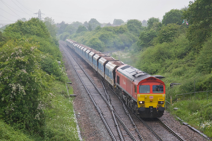 59203, 11.35 Merehead Quarry-Wootton Bassett FY, Clink Road Junction 
 On my way home I stopped off at Clink Road Junction, a favourite spot of mine back in the 1970s. As can be seen from one of my images taken then at .....https://www.ontheupfast.com/v/photos/21936chg/27043797604/x50001-07-50-paignton-london-paddington things have changed considerably. Apart from the loss of the signal box, the rampant vegetation growth has changed the scene so as to make it virtually unrecognisable! It's interesting to see that the railing along the side of the path that used to lead down to the signal box is one thing still extant from 1979. In the rain, 59203 is working hard hauling the 11.35 Merehead to Wootton Bassett loaded ballast train. 
 Keywords: 59203 11.35 Merehead Quarry-Wootton Bassett FY Clink Road Junction