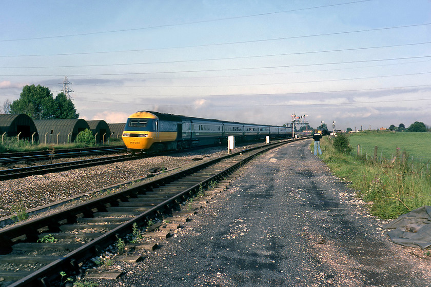 253033, down Golden Hind, Silk Mill Junction 
 Just over six months old HST set 253033 passes Silk Mill Junction just to the west of Taunton's Fairwater Yard with the down Golden Hind. I believe that this train was the 17.20 Paddington to Plymouth service but I am open to correction. This power car will be one of either W43135 or W43136 both of which completed their working lives on the Western Region until their end in 2019. Notice Graham a little further forward than where I am standing - he always had more confidence when taking photographs on railway land than me! 
 Keywords: 253033 down Golden Hind Silk Mill Junction HST 17.20 Paddington-Plymouth 43135 43136