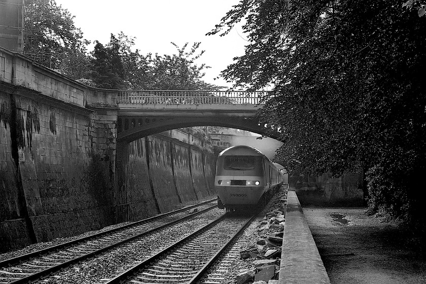 253008, unidentified up working, Sydney Gardens 
 A short distance east of Bath station is the superb Sydney Gardens, The GWML passes through the gardens in close proximity to the general public and the beautifully manicured lawns! Here, HST set 253008 (43016 and 43017) passes through the gardens with an unidentified up working for Paddington. During the planning of the GWML electrification programme, the issue of how to wire the section of line through Sydney Gardens caused a huge debate with suggestions that this should be a neutral section of the line free from wiring. In the end, the problem was solved by the decision to terminate the wiring at Thingley Junction some ten miles east of here but not before expensive preparations had been completed including the lowering of the track. 
 Keywords: 253008 up working Sydney Gardens