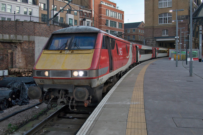 91122, GR 16.00 London KIng`s Cross-Edinburgh (1S24, 6L), London King`s Cross station 
 With the later afternoon light fading fast, 91122 waits at King's Cross' platform zero. It will work the 1S24 16.00 to Edinburgh Waverley. Notice the material stored to the left of the train, this was part of much more that was stored being used as part of the works to re-configure the throat of King's Cross including the re-opening of the third bore of the Gassworks Tunnels. 
 Keywords: 91122 16.00 London KIng`s Cross-Edinburgh 1S24 London King`s Cross station