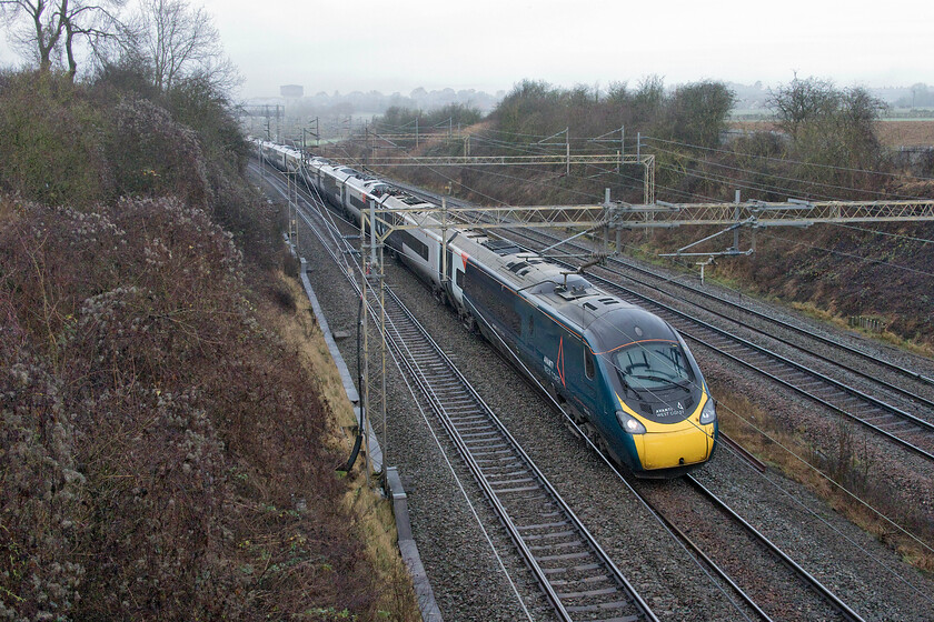 390131, VT 10.50 Birmingham New Street-London Euston (1B34, RT), Victoria bridge 
 390131 'City of Liverpool' sweeps around the reverse curve between Roade and Ashton in South Northamptonshire. The Avanti West Coast Pendolino is working the 10.50 Birmingham New Street to Euston service. It is services such as this, taking eighty-seven minutes stop to stop that HS2 will seek to usurp when it commences operations. Whenever this will happen, the same journey will take forty-nine minutes saving an impressive thirty-eight minutes. 
 Keywords: 390131 10.50 Birmingham New Street-London Euston 1B34 Victoria bridge Avanti West Coast Pendolino City of Liverpool