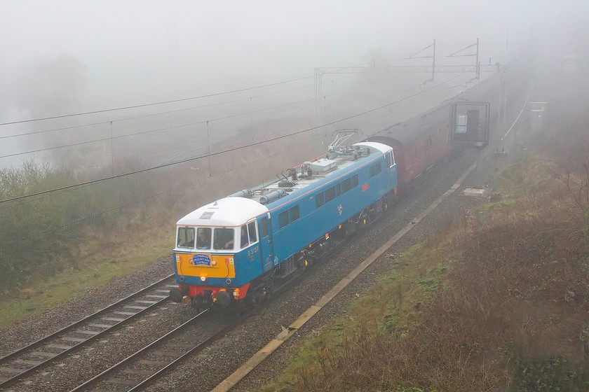 86259, outward leg of The Winter Cumbrian Mountain Express, 07.10 London Euston-Carlisle (1Z86), A45- Weedon bypass bridge 
 86259 'Les Ross/Peter Pan' cuts through the dense fog with the 1Z86 Winter on the Cumbrian Mountain Express railtour that left Euston a little later than its scheduled 07.10. The train is seen passing Weedon taken from the lofty heights of the new A45 bridge that is part of the bypass opened in December 2018. Unfortunately, the customers who paid to go on this railtour expected steam haulage up and over Shap returning via the Settle and Carlisle route were to be disappointed as 35018 'British India Line' was declared a failure at Carnforth before even being attached to the train so it was hauled by 47826. 
 Keywords: 86259 The Winter Cumbrian Mountain Express 07.10 London Euston-Carlisle 1Z86 A45- Weedon bypass bridge