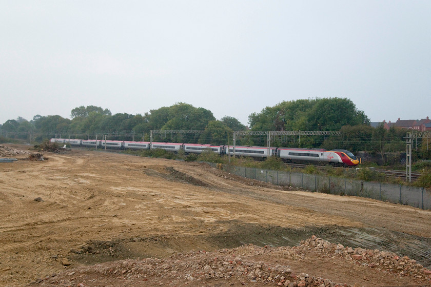 Class 390, VT 07.30 London Euston-Glasgow Central (1S42), site of Roade station 
 A class 390 passes the flattened site of the old Pianofort site in the village of Roade on the WCML, the 07.30 Euston to Glasgow Central 1S42 heads north. Before allowing the construction of yet more houses, might planners first consider infrastructure such as to reinstate Roade's station that was located just to the right of the image? 
 Keywords: Class 390 07.30 London Euston-Glasgow Central 1S42 site of Roade station