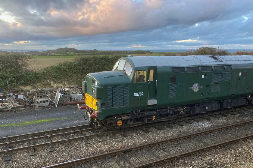 D6732, stabled, Weybourne yard 
 Long term resident of the North Norfolk Railway's diesel fleet is Type 3 D6732 that first arrived on the railway in September 1994. It sees regular use throughout the year but is not actually owned by the railway but is privately owned. It has been a reliable performer apart from during the winter of 2018/2019 when it was taken to Barrow Hill for attention to its main generator. In its mainline career it carried two other numbers, 37032 and 37353. In June 1989 it reverted back to 37032 again. It is seen here standing catching some very late afternoon light in Weybourne's silent yard. 
 Keywords: D6732 Weybourne yard D6732 37032 37353 37032