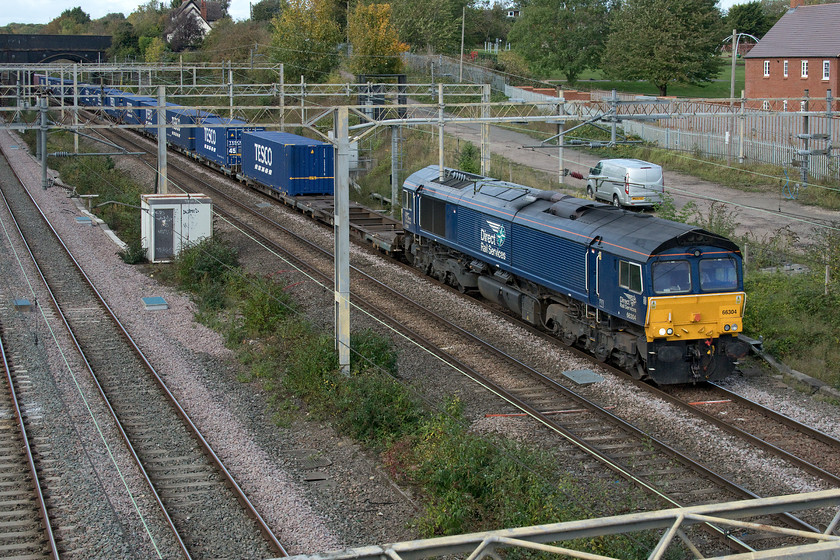 66304, 13.50 DIRFT-Ripple Lane (4L45, 1E), site of Roade station 
 The daily southbound Tesco Express 4L45 is seen passing Roade at the site of the old station in semi-shaded conditions as the sun had just popped behind a cloud but at least the driver was happy as he gave Andy and I a good blow on the horn as he approached! This 13.50 (or thereabouts) Daventry to Ripple Lane is a seven day a week operation as is the return northbound service. The unloaded containers are heading south to be filled and return next day ending up at the food giant's huge distribution centre at Crick. These trains even enter and leave the depot on their own dedicated spur of track all in an effort to keep the food giant's supply chain going and the shelves filled and to keep us consumers happy! 
 Keywords: 66304 13.50 DIRFT-Ripple Lane 4L45 site of Roade station DRS Direct Rail Services Tesco Express