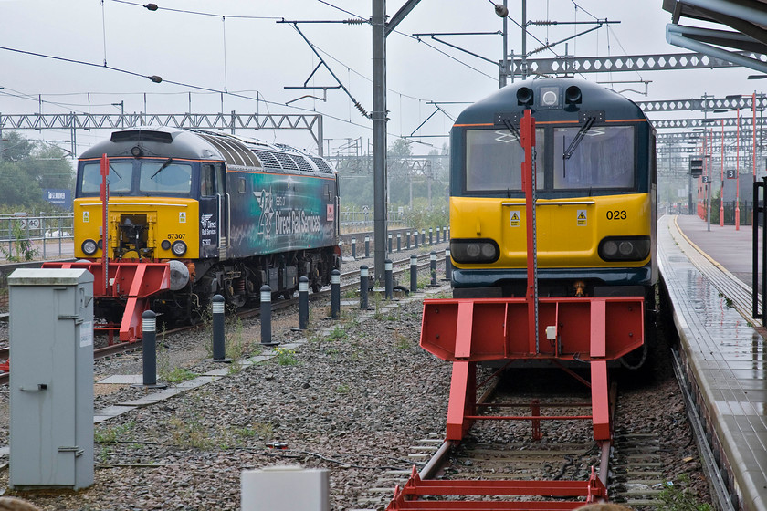 57307 & 92023, stabled thunderbirds, Rugby station 
 At a wet and grey Rugby 57307 'Lady Penelope' sits next to 92023 to the south end of the station. The DRS Class 57 is stabled in its role as a thunderbird resue locomotive but I am not sure as to why the Class 92 is present on the rarely used platform three road. 92023 remains in its BR two-tone grey livery and formally was named 'Ravel'. 
 Keywords: 57307 92023 thunderbirds Rugby station DRS Direct Rail Services Lady Penelope