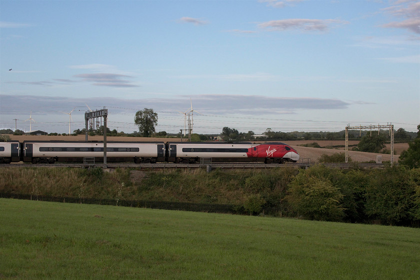 390044, VT 14.40 Glasgow Central-London Euston (1M15, 31L), Roade Hill 
 390044 is over half an hour late passing Roade Hill north of Milton Keynes with the 1M15 Glasgow Central to London Euston. Despite the blue sky behind the train, a very awkward bank of cloud behind me kept the line in the shade until I left when it dissipated! The M1 wind farm can be seen in the background. 
 Keywords: 390044 14.40 Glasgow Central-London Euston 1M15 Roade Hill