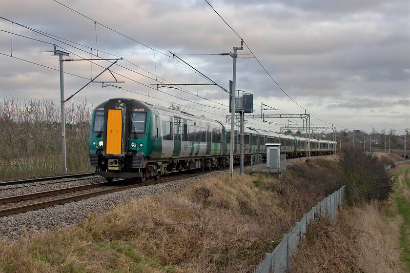 350374 & 350259, LN 14.38 Northampton-Birmingham New Street (2Y67, 1L), Wilson's Crossing 
 What a difference ten minutes makes! A short time after the previous image was recorded some troublesome cloud drifted in and blotted out the afternoon sunshine; back to normal then! 350374 and 350259 work the 14.38 Northampton to Birmingham all stations stopper 2Y67 service. I glanced through the windows against the sky as this train passed and saw very few passengers. Normally, (whatever that is now?) trains on New Year's Eve to either Birmingham or London would be packed with revellers but COVID-19 has put paid to that for the last two years. 
 Keywords: 350374 350259 14.38 Northampton-Birmingham New Street 2Y67 Wilson's Crossing London Northwestern Desiro