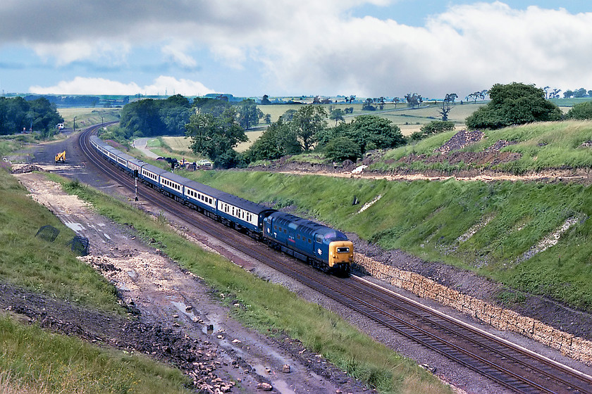 55022, 09.00 Edingburgh-London Kings Cross (1E05), High Dyke SK942289 
 At last the sun has come out, but not for long! It shines down on 55022 'Royal Scots Grey' about to crest Stoke summit as it enters the tunnel of the same name. It has 101 miles left to run into King's Cross with the 1E05 09.00 from Edinburgh. The yellow earth mover to the left indicates that the work to clear the sidings at High Dyke and the improvements to the area in the cutting in the foreground has not been completed. The removal of the concentration sidings that were used to marshall ironstone wagons from the nearby mines towards Colsterworth has recently been completed. Virtually all of this area today is totally overgrown and, off course, completely inaccessible to the young photographer (as I was in 1978!) 
 Keywords: 55022 09.00 Edingburgh-London Kings Cross 1E05 High Dyke SK942289