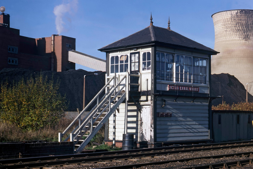 Acton Canal Wharf Signal Box (Midland, 1894) TQ211829 
 The delightful Acton Canal Wharf signal box is seen in the November sunshine. It is a Midland Railway type 2b box that was opened in 1884. As the name suggests, it is located just above the Grand Union canal that passes under the line just to my right. Behind the box is the old Acton Lane coal-fired power station that was still open and generating some 150mw of energy until it closed in 1983. Whilst the power station has been demolished, now the home of the Powergate Business park, the box is still in existence. It has been extended and UPVC clad meaning that it ornate Midland styling has been totally lost behind a mass of white plastic, the best image that I have secured was taken from a great distance caused by the HS2 works taking over the area, see...... https://www.ontheupfast.com/p/21936chg/28768437004/acton-canal-wharf-signal-box-midland 
 Keywords: Acton Canal Wharf Signal Box TQ211829