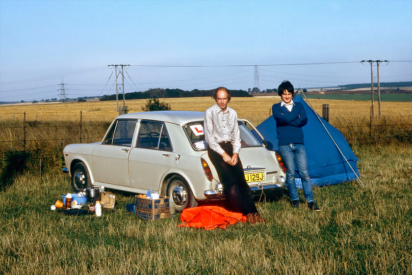 Graham & me, camping spot, Essendine TF043129 
 After spending a very windy night in the trusty tent just next to the ECML at Essendine Graham and I pose for the camera in the early morning sunshine that was, unfortunately, not to last! Notice the L plate attached to the Austin 1100. Yes, I was learning to drive at this time with Graham permitting me to drive UVJ 129J with him riding pillion. With the permission of the land owner, we left the tent erected in the field whilst we went off for the day returning for another night.