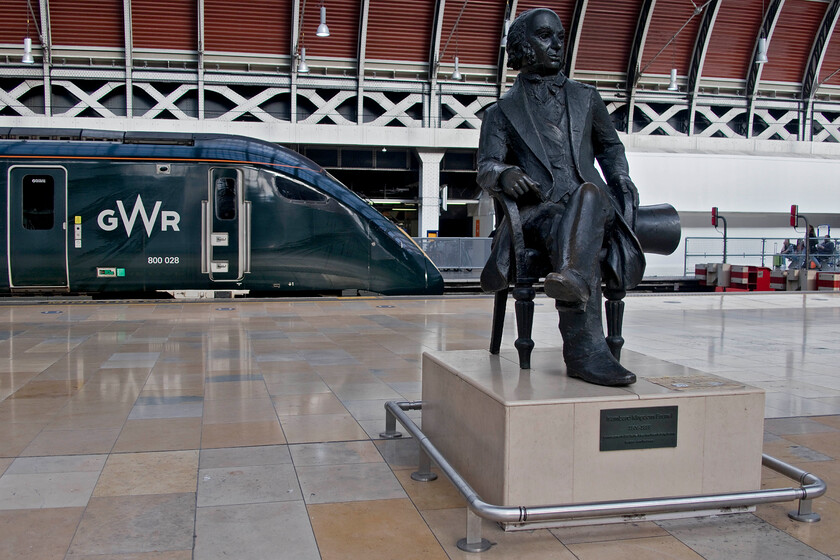 802028, GW 10.56 Swansea-London Paddington (1L18, RT) & IKB, London Paddington station 
 With the rather small and unassuming statue of Brunel sitting comfortably under his grand train shed at Paddington the world goes on around him. The great station at the eastern end of God's Wonderfull Railway was one of his finest structures and testament to its design is that is now one hundred and sixty years old and still serving passengers as it was designed to! Behind him, GWR's 1L18, the 10.56 from Swansea, has recently arrived. I wonder what IKB would have thought of the latest trains to run in and out of his station and especially about their recent withdrawal from service due to cracks on the yaw damper mounts? 
 Keywords: 802028 10.56 Swansea-London Paddington 1L18 IKB, London Paddington station GWR IET Brunel