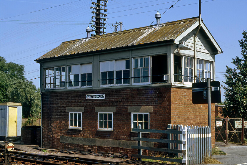 Moreton-on-Lugg signal box (GWR, 1943) 
 Moreton-on-Lugg signal box is seen in the summer sunshine. It is the next box north of Hereford on the route towards Shrewsbury. The 1943-built forty-four lever box demonstrates the GWR more austere design of box with a much simpler gabled roof that is clad with corrugated white asbestos sheets. I last visited the box in 2016 and found the box recognisable to what it did back here in 1981 even down to the notice on the gate in the background, see...... https://www.ontheupfast.com/p/21936chg/25752988204/moreton-lugg-signal-box 
 Keywords: Moreton-on-Lugg signal box GWR 1943