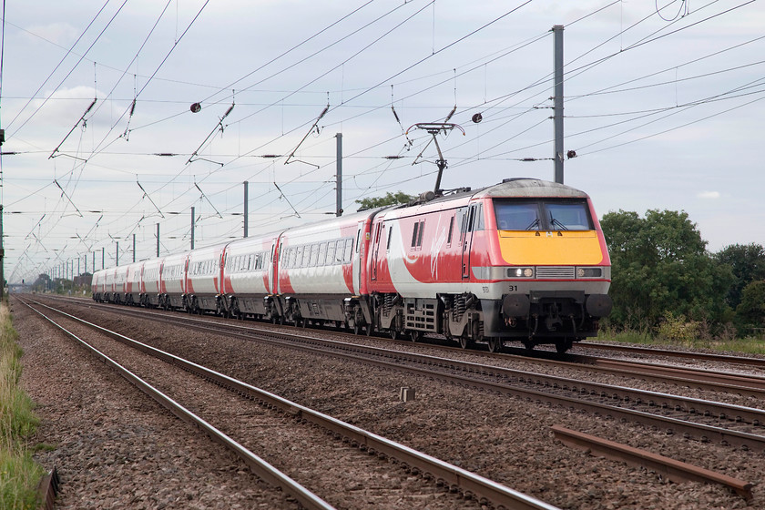 91131, GR 10.08 London Kings Cross-Newcastle (1B92. RT), Holme Green Crossing TL192426 
 The four mile section of the ECML between Arlesey and Biggleswade is virtually dead straight. This means a line speed of 125mph can be adopted by trains capable of it. Here, 91131 passes Holme Green farm crossing leading the 10.08 King;s Cross to Newcastle that should be dong line speed. 
 Keywords: 91131 1B92 Holme Green Crossing TL192426