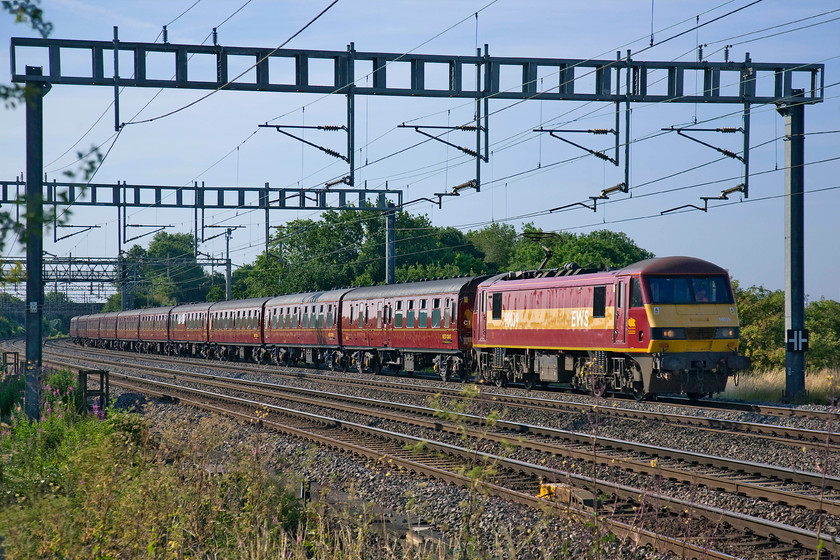 90039, outward leg of The Cumbrian Mountain Express, 07.10 London Euston-Carnforth (for steam onwards) (1Z86), Ashton Road bridge 
 I am not a fan of West Coast Railway's rather drab livery as it does not always photograph particularly well. However, with a (sort of!) matching locomotive in the form of 90039 and in the early morning summer sunshine against lush greenery, it looks quite good. A uniform set of their stock heads north past Ashton Road bridge just south of Roade, as the outward leg of The Cumbrian Mountain Express. The charter left Euston at 07.10 running as 1Z86 to Carnforth where passengers enjoyed haulage behind 46115 'Scots Guardsman' over Shap to Carlisle. 
 Keywords: 90039 The Cumbrian Mountain Express 07.10 London Euston-Carnforth for steam onwards 1Z86 Ashton Road bridge WCR West Coast Railways