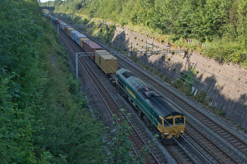 66519, 03.00 Felixstowe North-East Midlands Gateway (4M86, 23E), Roade cutting 
 Close examination of this photograph reveals that the tail end of the 4L52 Freightliner service is just going around the curve and out of Roade cutting. 66519 leads the 4M86 03.00 Felixstowe North to East Midlands Gateway that had I been standing on Hyde Road bridge in the distance I would not have been able to capture due to them crossing each other. 
 Keywords: 66519 03.00 Felixstowe North-East Midlands Gateway 4M86 Roade cutting Freightliner