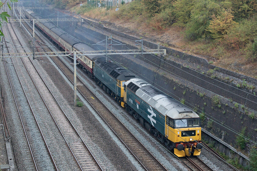 47593 & 47614, 08.20 Crewe HS-Southall LS (5Z64, 7E), Roade cutting 
 I was almost caught napping here taking this photograph! I was expecting the 08.20 Crewe HS to Southall Locomotive Services empty coaching stock to be making fairly leisurely progress up through Roade cutting but when it appeared, amidst clouds of exhaust, it was really moving so I had to rapidly adjust the shutter speed from 1600th to 2000th second. 47593 'Galloway Princess' leads 47614 (not powered) making a fine sight hauling a set of blood and custard preserved stock. 
 Keywords: 47593 47614 08.20 Crewe HS-Southall LS 5Z64 Roade cutting