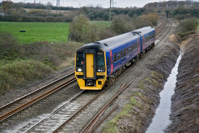 158956, GW 13.10 Weymouth-Gloucester (2E24), Berkley ST806498 
 As well as on the up side of this bridge close to the hamlet of Berkely just east of Frome, the down side has also been cleared and drainage work has been undertaken. This view was horribly hampered by rampant vegetation growth that had competely covered the culvert, in fact, I did not even know that there was one there! It looks as though the operator of the rail-mounted dredger that was clearing the culvert did not have a very good aim when dumping the spoil in the wagons looking at the state of the tack and trackbed! 158956 is working the 2E24 13.10 Weymouth to Gloucester service via a reversal at Bristol Temple Meads. 
 Keywords: 158956 13.10 Weymouth-Gloucester 2E24 Berkley ST806498 First Great Western