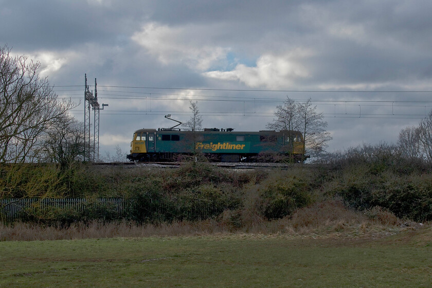 86632, 11.17 Northampton-Crewe Basford Hall LE (0Z90, 9E), Wilson's Crossing 
 A pretty shocking photograph of what is, after all, just a light engine! However, could this be the last photograph I take of a Freightliner Class 86 on the mainline? Now sidelined from working Freightliners for the company of the same name most are out of hours or out of exams with just two or three still able to operate. This one has just left Northampton on a crew training/route familiarisation light engine move running as 0Z90 back to Crewe Basford Hall. Unfortunately, it trundled past me here at Wilson's Crossing just north of Northampton as I was walking towards the line so this is all I could manage but it's possibly history in the making! 
 Keywords: 86632 11.17 Northampton-Crewe Basford Hall LE 0Z90 Wilson's Crossing Freightliner AL6