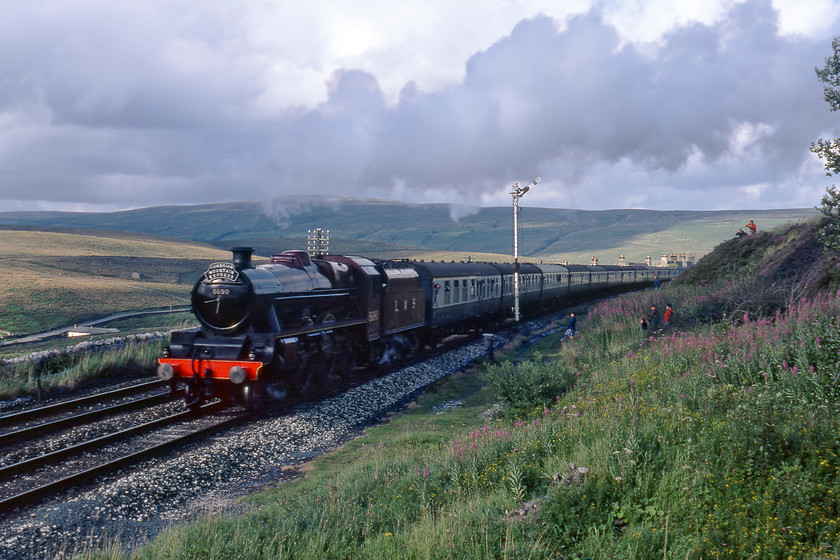 5690, outward leg of The Cumbrian Mountain Express, Garsdale 
 After rushing from our previous spot north of Ais Gill summit we reached Garsadle just in time to capture 5690 'Leander' leaving after a shortened water and photo stop. It was shortened due to it being running very late after the locomotive was detached to rescue a freight a little earlier in the afternoon. After being absent earlier the sun has now come out but this has put me the wrong side of the train spoiling the image somewhat! At least the tape recording made is a little better. This can be enjoyed at ...... https://youtu.be/LLqHkENmPkA 
 Keywords: 5690 outward leg of The Cumbrian Mountain Express Garsdale Leander