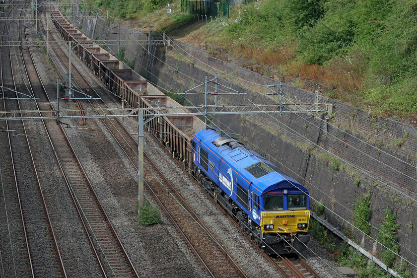 66142, 11.59 Burton-ot-Wetmore-Acton TC (6V06, 9L), Roade cutting 
 Namer 5 - 66142 'Maritime Intermodal Three'

As the work to complete HS2 grinds relentlessly on more and more waste is heading north from various worksites for disposal at several carefully selected locations. One of the empties heads south after depositing its load in the Trent Valley lead by 66142 'Maritime Intermodal Three'. The 6V06 11.59 Burton-ot-Wetmore to acton TC is seen passing through Roade cutting on what is now a warm and sunny weekday afternoon. 
 Keywords: 66142 11.59 Burton-ot-Wetmore-Acton TC 6V06 Roade cutting Maritime Intermodal Three