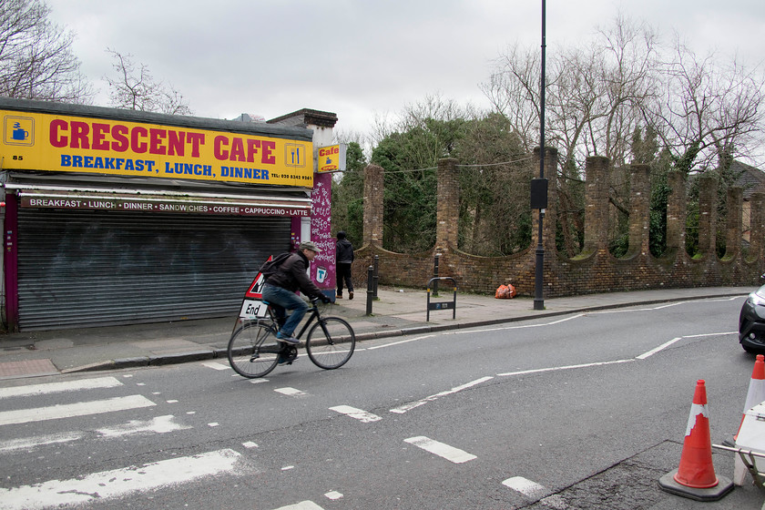 Former frontage, Crouch End station 
 It looks like the Crescent Caf has not sold a cup of tea, let alone serve a dinner for some time! This is all that remains of the Great Northern's station building on Crouch End Hill. The caf features in many contemporary photographs even though it has a different appearance to how it is seen here. The main station building was located where the strange inverted brick arches are seen in front of the trees. It is a misnomer that these arches are the actual remains of the original structure; they were constructed after the building was razed to the ground in 1977. The pathway between the caf and the structure is the access down some steps to the Parkland Walk on the trackbed that passes below the bridge. 
 Keywords: Former frontage Crouch End station