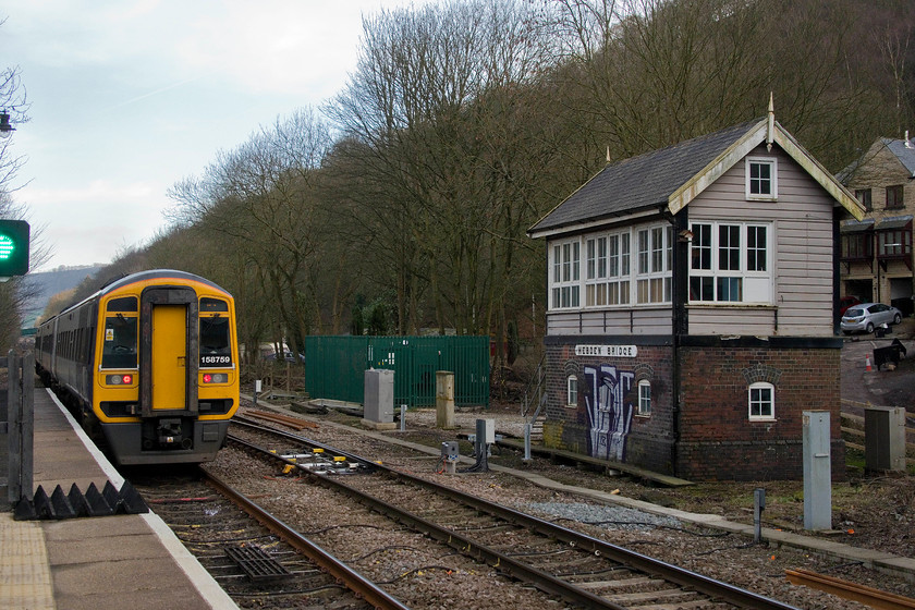 158759, NT 14.47 Preston-York (1B32, 3L), Hebdon Bridge station 
 158759 leaves Hebdon Bridge station working the 14.47 Preston to York service. It has just passed the recently redundant signal box that has, unfortunately, already been the subject of a graffiti attack. In October 1986, I took a virtually identical picture to this except the unit was a class 101 Metro Cammell DMU that was also on a York service according to its destination blind. 
 Keywords: 158759 14.47 Preston-York 1B32 Hebdon Bridge station