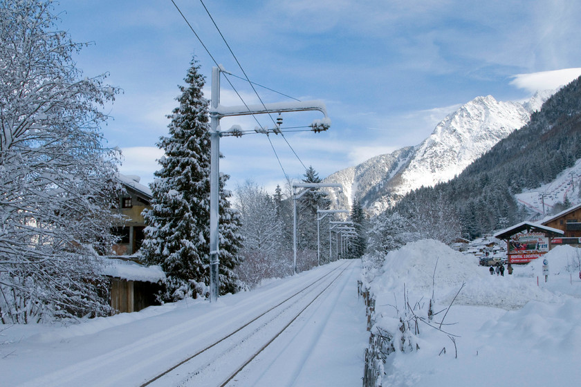 Chamonix-Montenvers Mer de Glace line looking northeast, Chemin du Pied-du Grepon foot crossing 
 Taken from a snow-covered foot crossing in Chamonix, the Montenvers mountain railway is seen. Looking at the exposed track it looks as though a train has recently passed but due to the weather it was closed to passengers according to signs at the station. Despite the sunny weather, it was a very cold morning, and Chamonix is at 1000m altitude (3200feet). 
 Keywords: Chamonix-Montenvers Mer de Glace line looking northeast Chemin du Pied-du Grepon foot crossing