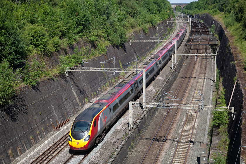 390126, VT 08.47 Liverpool Lime Street-London Euston (1A15), Roade Cutting 
 At the northern end of Roade Cutting the fast and slow routes begin a more determined separation since leaving London. The fast lines curve sharply off towards Rugby via the Weedon Loop and the slow lines to the right head off towards Northampton. In this view, the fabled 'bird cage', as it is known, can be seen over the slow lines. This was installed following a collapse of the cutting in 1890, it was subsequently raised to accommodate the electrification wires in the early 1960s. 390126 'Virgin Enterprise' passes through with the 08.47 Liverpool Lime Street to Euston. 
 Keywords: 390126 1A15 Roade Cutting