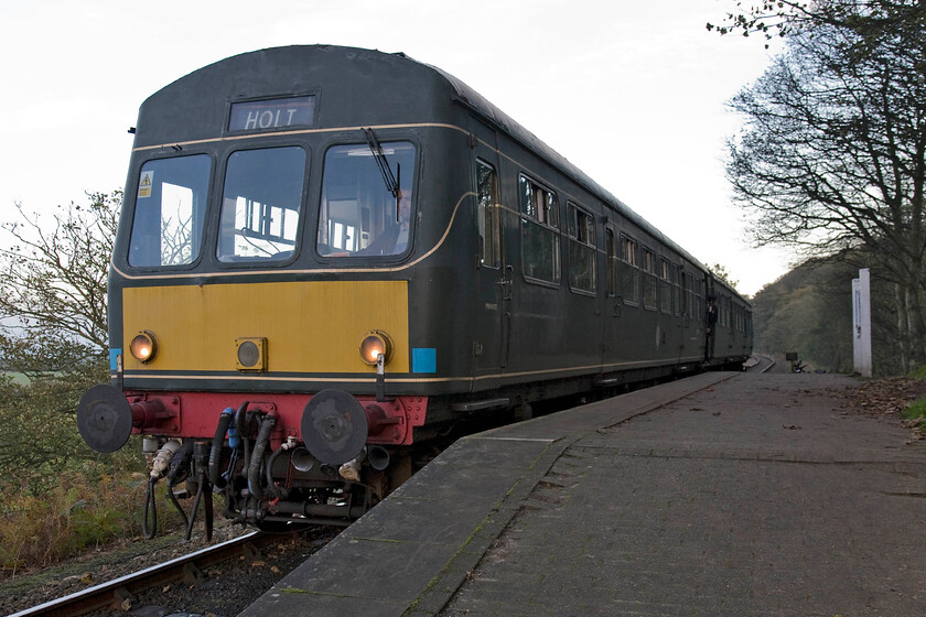 M51192 & M56352, 15.45 Sheringham-Holt, Kelling Heath Park station 
 After arrival back at Kelling from our bike ride, I walked down to the North Norfolk Railway in the late afternoon falling light. With no passengers alighting or joining the 15.45 Sheringham to Holt it pauses at Kelling Heath station it makes ready to leave with the guard about to give the buzzer two rapid presses. The Class 101 DMU is formed of M51192 and M56352 that both look a little worse for wear with rather faded green paintwork. 
 Keywords: M51192 M56352 15.45 Sheringham-Holt Kelling Heath Park station Class 101 DMU