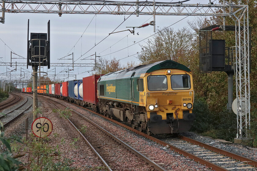 66539, 12.16 Lawley Street-London Gateway (4L46, 2E), Wolverton station 
 With a toot from the driver, 66539 leads the well-loaded 12.16 Laweley Street to London Gateway daily Freightliner through Wolverton station. The troublesome lilac and ash sapling both now established on the down-slow platform ramp at Wolveron are going to make this shot very tricky soon unless they are removed. 
 Keywords: 66539 12.16 Lawley Street-London Gateway 4L46 Wolverton station Freightliner