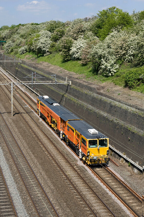 Track machine, unidentified up working, Roade cutting 
 Unfortunately, I was unable to identify both this working and the Colas operated Plasser & Theurer machine switch and crossing tamper operating it! Unlike other units of this type, this particular one has its DR73XXX number written smaller and higher up on the cab side and in this photograph the wires cut right through it making it illegible! Never mind, it's nice to see a bit of Dutch orange brightening up Roade cutting! 
 Keywords: Plasser Theurer switch (points) and crossing tamper