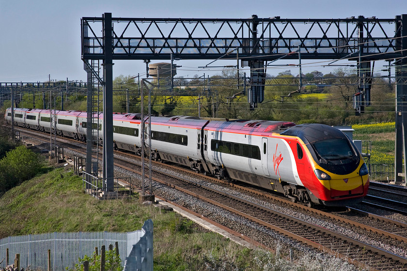 390050, VT 15.35 Manchester Piccadilly-London Euston (1A52), Roade Hill 
 With Roade's water tower clearly visible through the gargantuan gantry that holds just two colour lights for the up slow and fast lines Virgin's 390050 leads the 1A52 15.35 Manchester to Euston service. Even using the zoon lens at this location it has proved impossible to crop out the recently installed palisade fencing. 
 Keywords: 390050 15.35 Manchester Piccadilly-London Euston 1A52 Roade Hill Virgin West Coast Pendolino