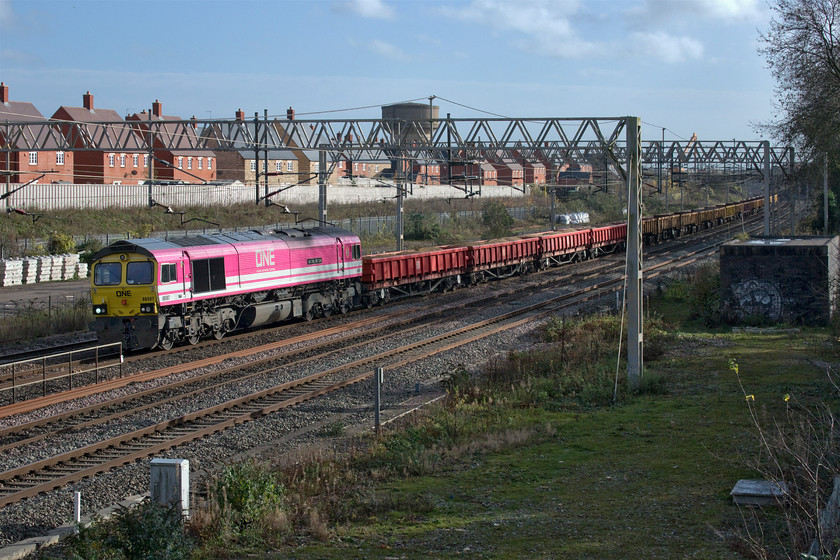 66587, 09.49 Hanslope Junction-Crewe Basford Hall (6Y60, 21E), site of Roade station 
 Having been involved in an overnight possession near Blisworth 66587 'As One, We Can' had gone south to Bletchley earlier in the morning where the loco. had run round. It is seen passing Roade in some pleasant November sunshine leading the 6Y60 09.49 Hanslope Junction to Crewe Basford Hall made up of a combination of JNA (ballast), IEA-A (ballast) and FEA (track panels) wagons. The one-off livery was applied to 66587 back in June 2019 to commemorate Freightliners partnership with ONE (OceanNetworkExpress) a new global container shipping company whose distinctive boxes are becoming increasingly common on Freightliner and Intermodal services. At the unveiling and naming ceremony held at Southampton docks, it was also announced that all the Freightliner liveried Class 66s would steadily turn from green to a new black and orange livery with the company having been acquired by Genesee & Wyoming. So far, limited progress has been made with this. Thanks to Mike for the reporting number. 
 Keywords: 66587 09.49 Hanslope Junction-Crewe Basford Hall site of Roade station As One, We Can